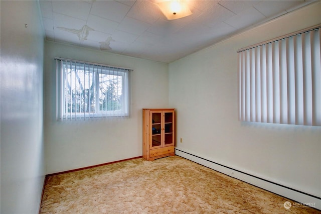 carpeted spare room with a baseboard heating unit