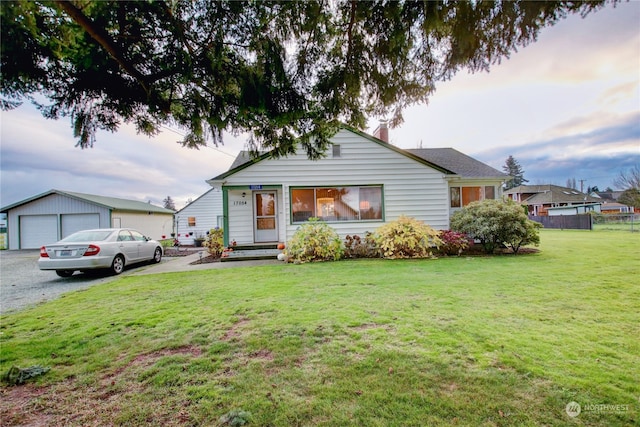 view of front facade featuring a garage, an outbuilding, and a front lawn