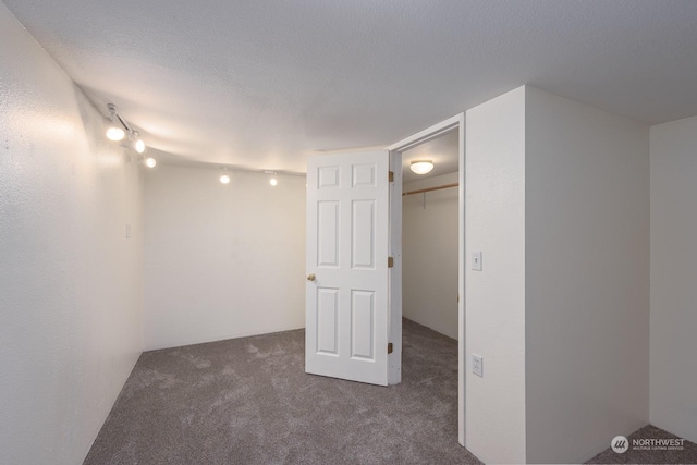 unfurnished room with dark colored carpet and a textured ceiling