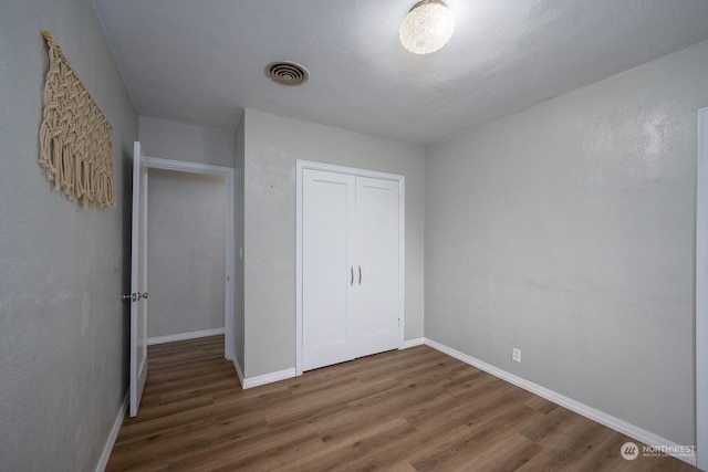 unfurnished bedroom with dark hardwood / wood-style floors and a closet