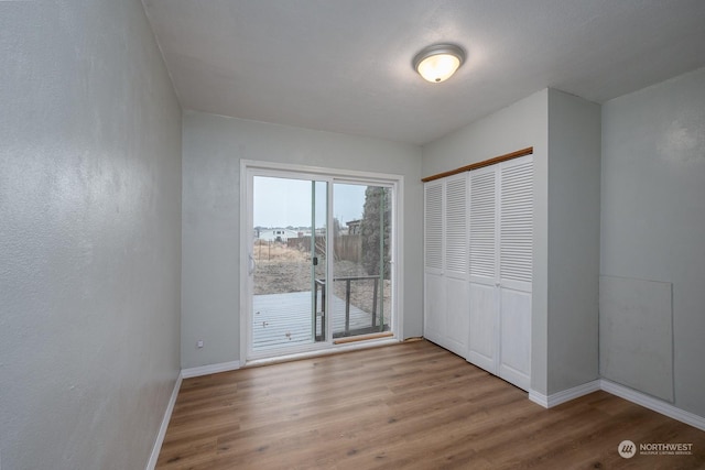 unfurnished bedroom with access to exterior, a closet, and light wood-type flooring