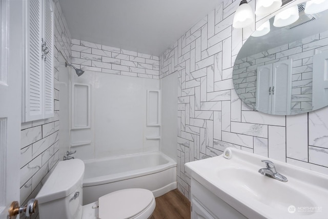 full bathroom with tub / shower combination, vanity, hardwood / wood-style flooring, tile walls, and toilet