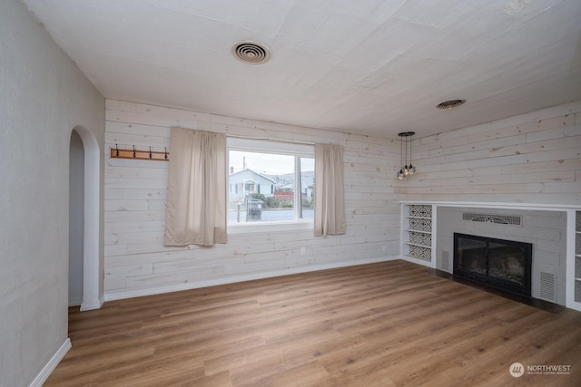 unfurnished living room with wood walls and wood-type flooring