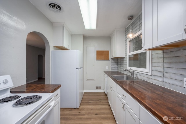 kitchen featuring white appliances, sink, tasteful backsplash, white cabinetry, and butcher block counters