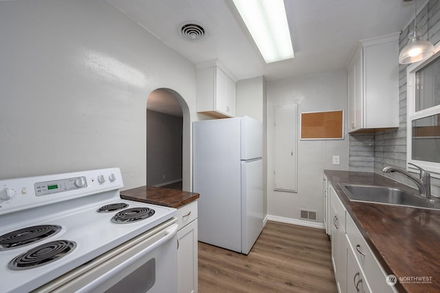 kitchen with backsplash, white appliances, sink, white cabinets, and butcher block countertops