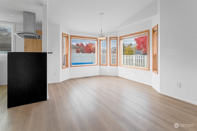 unfurnished dining area with light hardwood / wood-style floors and lofted ceiling