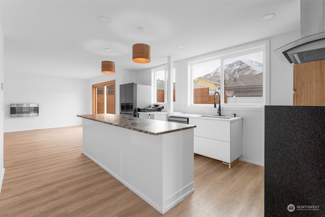 kitchen featuring stainless steel appliances, sink, pendant lighting, light hardwood / wood-style flooring, and white cabinets