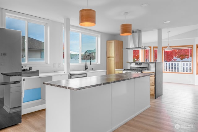 kitchen with sink, stainless steel appliances, pendant lighting, island range hood, and light wood-type flooring