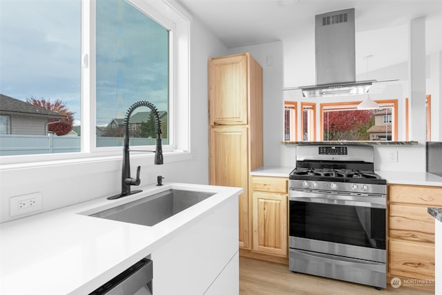 kitchen with sink, stainless steel gas stove, exhaust hood, and light brown cabinets