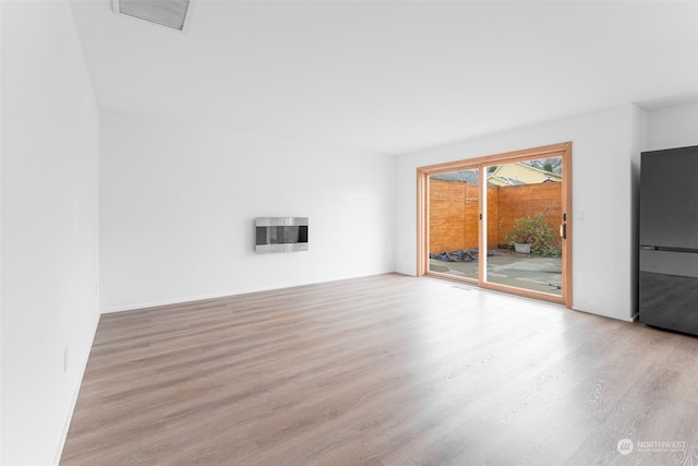 unfurnished living room with heating unit and light hardwood / wood-style flooring