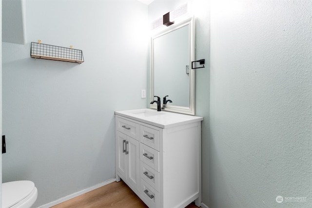 bathroom with hardwood / wood-style floors, vanity, and toilet