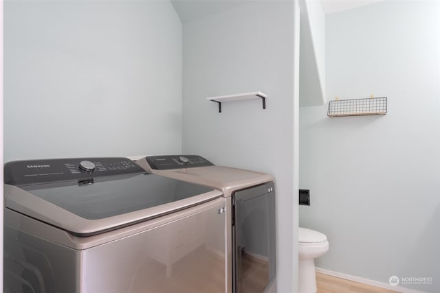 laundry area with washing machine and dryer and light hardwood / wood-style flooring