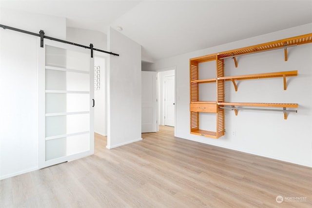 340 Brandi Ln, Wenatchee, WA 98801 - unfurnished bedroom featuring a barn door, wood finished floors, lofted ceiling, baseboards, and a closet