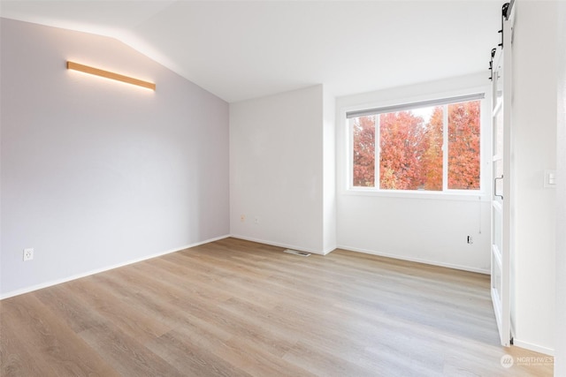 340 Brandi Ln, Wenatchee, WA 98801 - spare room with a barn door, light wood-style floors, vaulted ceiling, and baseboards
