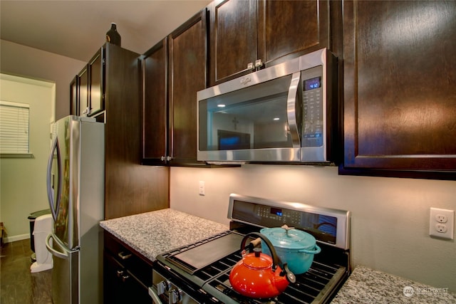 kitchen with dark brown cabinets, light stone countertops, and stainless steel appliances