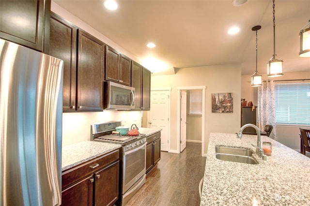 kitchen featuring light stone countertops, stainless steel appliances, dark wood-type flooring, sink, and pendant lighting