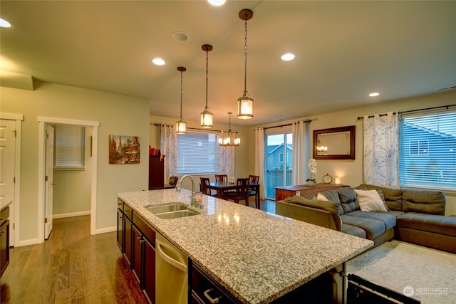 kitchen with dishwasher, sink, dark hardwood / wood-style floors, decorative light fixtures, and a center island with sink