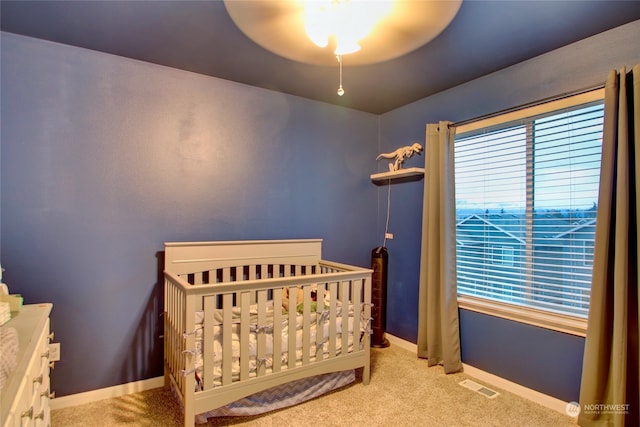 carpeted bedroom featuring ceiling fan and a nursery area