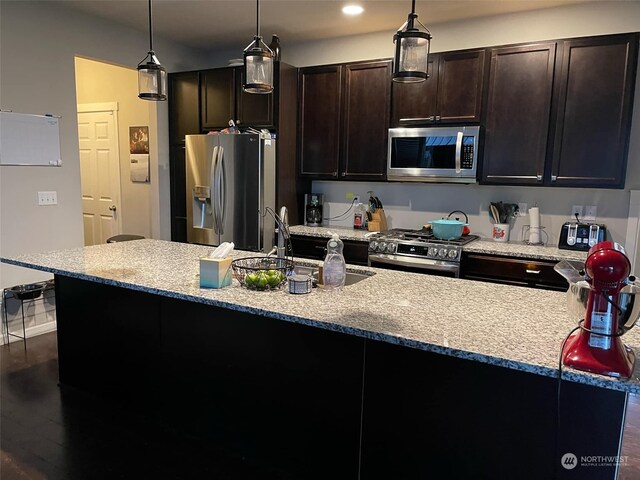 kitchen with dark hardwood / wood-style floors, sink, stainless steel appliances, and hanging light fixtures