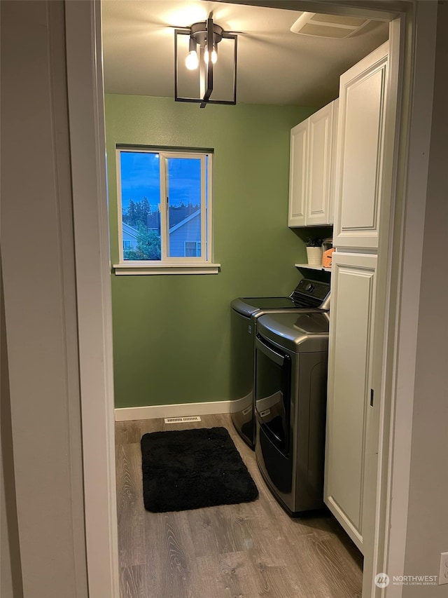 washroom featuring cabinets, separate washer and dryer, and light wood-type flooring