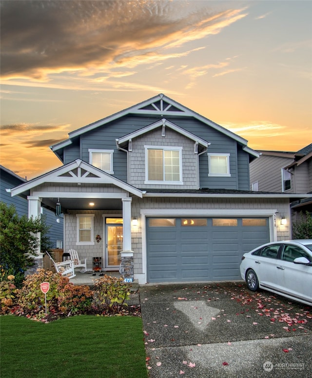 view of front of property featuring covered porch, a garage, and a lawn