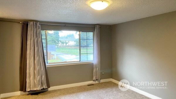 carpeted empty room with a textured ceiling