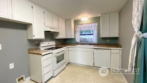 kitchen with white cabinetry, white appliances, and sink