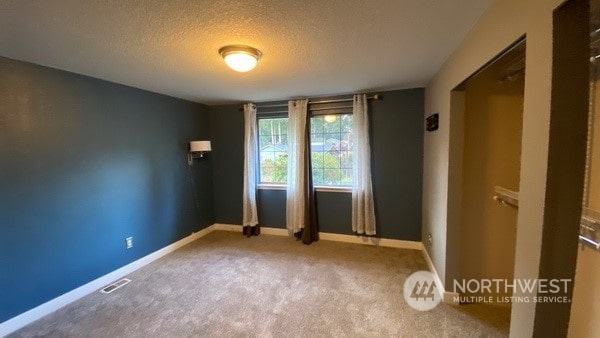 carpeted spare room with a textured ceiling