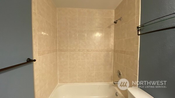 bathroom with toilet and tiled shower / bath