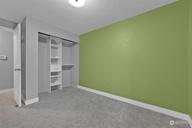 unfurnished bedroom with carpet flooring, a textured ceiling, and a closet