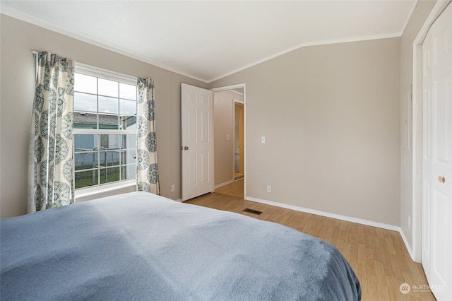 bedroom featuring crown molding, lofted ceiling, and light wood-type flooring