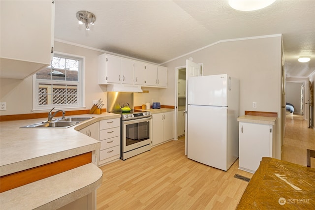 kitchen with stainless steel range with electric cooktop, sink, white fridge, white cabinetry, and lofted ceiling