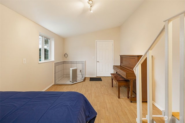 bedroom featuring wood-type flooring, vaulted ceiling, and radiator