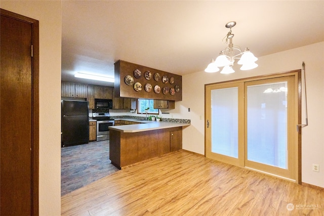 kitchen featuring kitchen peninsula, light wood-type flooring, black appliances, decorative light fixtures, and a chandelier