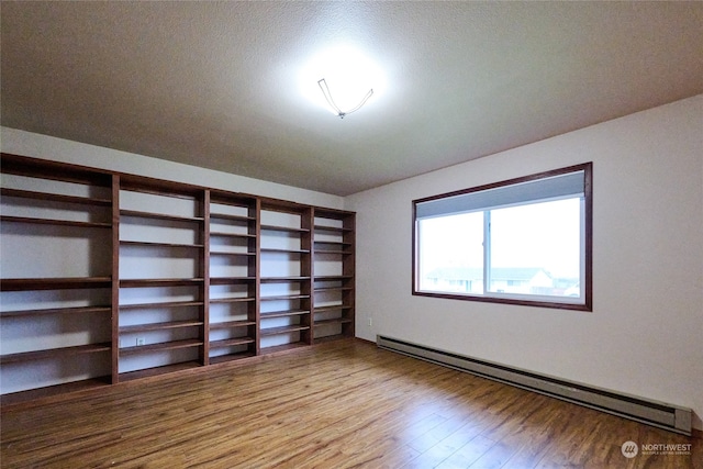 unfurnished bedroom featuring hardwood / wood-style flooring, a textured ceiling, and a baseboard radiator