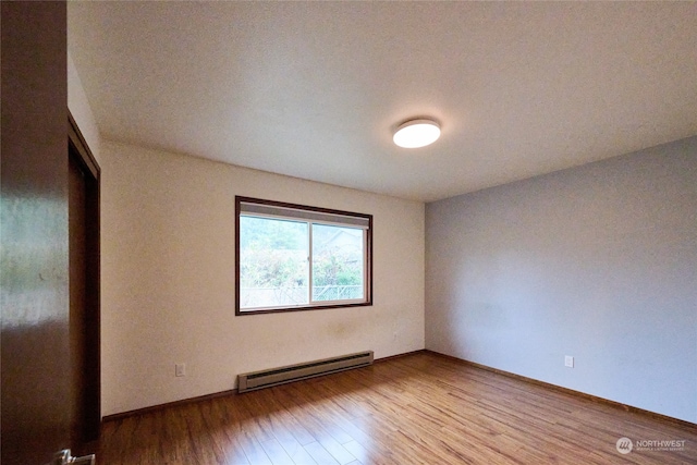 spare room with hardwood / wood-style floors and a baseboard radiator