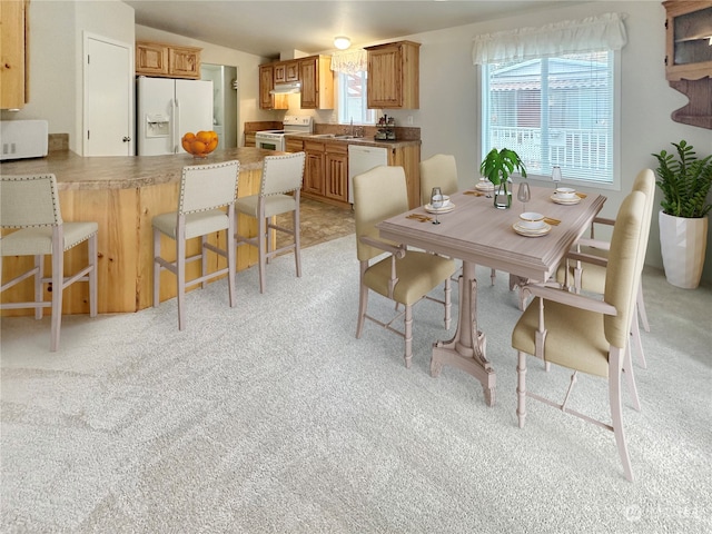 carpeted dining area featuring sink and vaulted ceiling