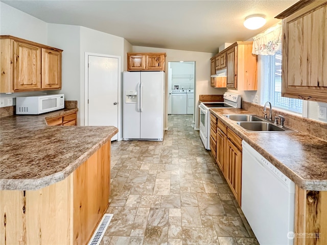 kitchen featuring white appliances, vaulted ceiling, washer and clothes dryer, and sink