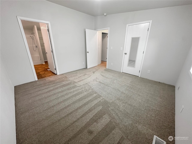 unfurnished bedroom with light carpet and connected bathroom