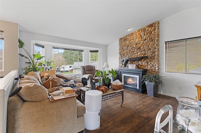 living room with a stone fireplace, hardwood / wood-style floors, and vaulted ceiling