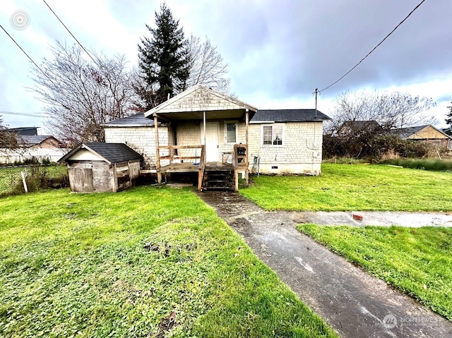 bungalow-style home featuring covered porch, a storage shed, and a front yard