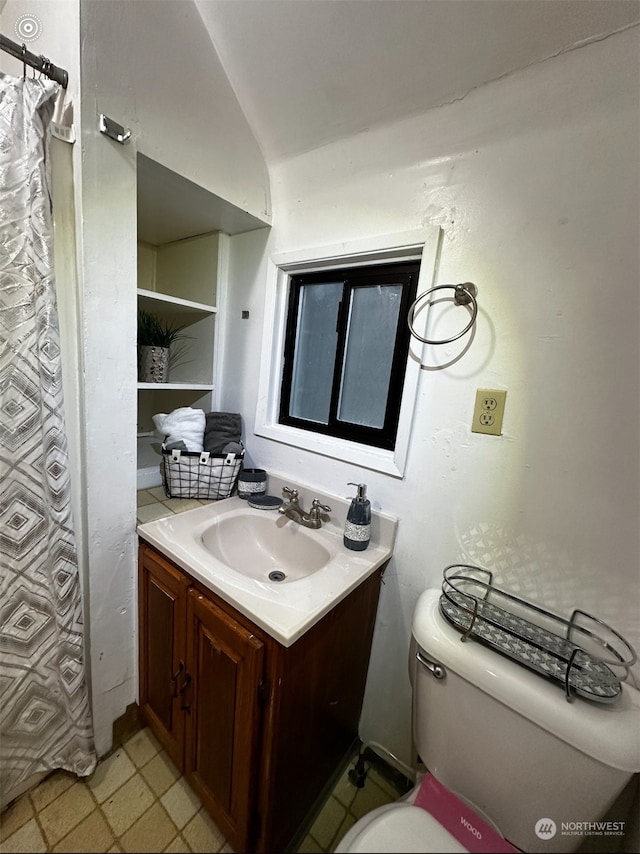 bathroom featuring vanity, toilet, and lofted ceiling