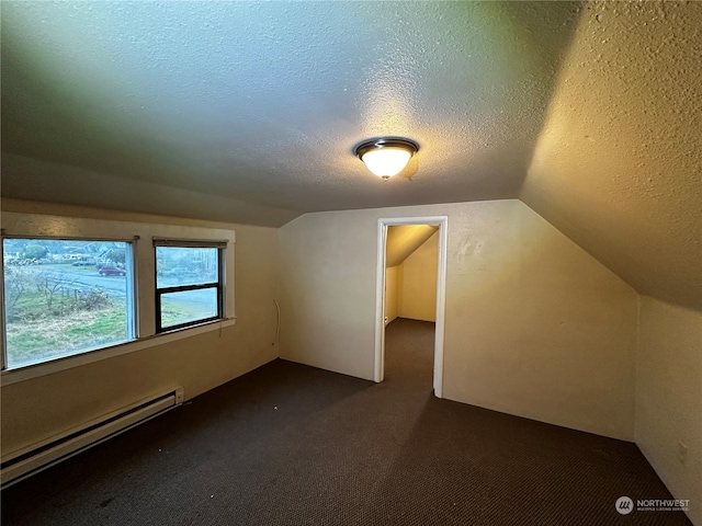 additional living space with dark colored carpet, baseboard heating, a textured ceiling, and vaulted ceiling