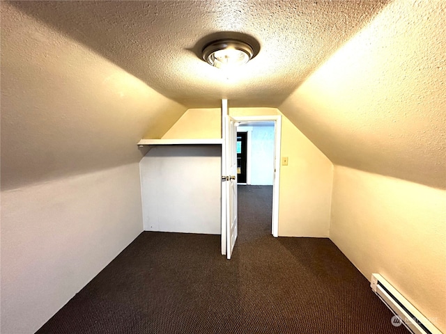 additional living space with dark colored carpet, lofted ceiling, a textured ceiling, and a baseboard radiator