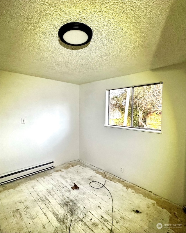 spare room featuring hardwood / wood-style floors, a textured ceiling, and a baseboard radiator