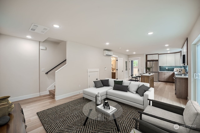 living room featuring light hardwood / wood-style flooring and a wall mounted AC