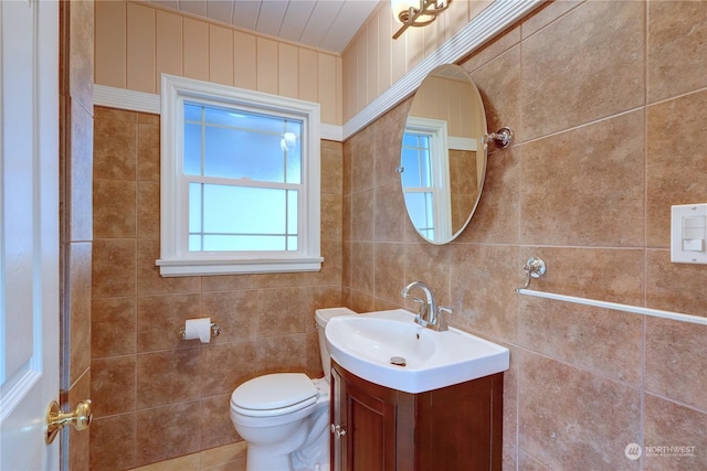 bathroom with vanity, toilet, and tile walls