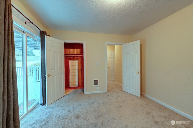 unfurnished bedroom featuring light carpet, a textured ceiling, and a closet