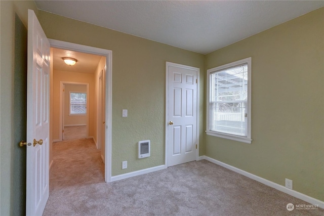 unfurnished bedroom with heating unit and light carpet