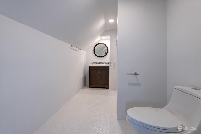 bathroom featuring tile patterned flooring, vanity, toilet, and lofted ceiling